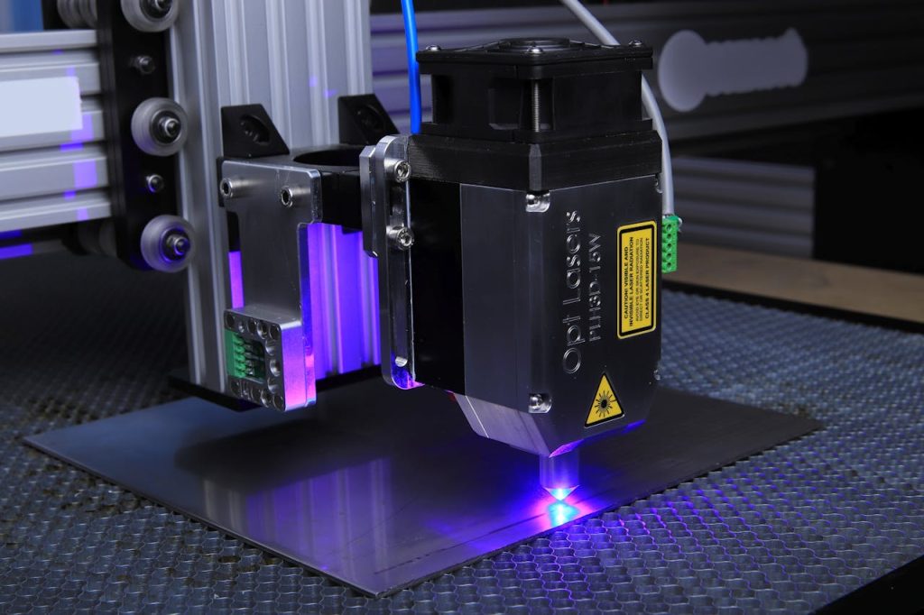 The Art of Drawing Readers In: Your attractive post title goes here Close-up of a laser engraving machine operating on a metal surface with blue laser light.